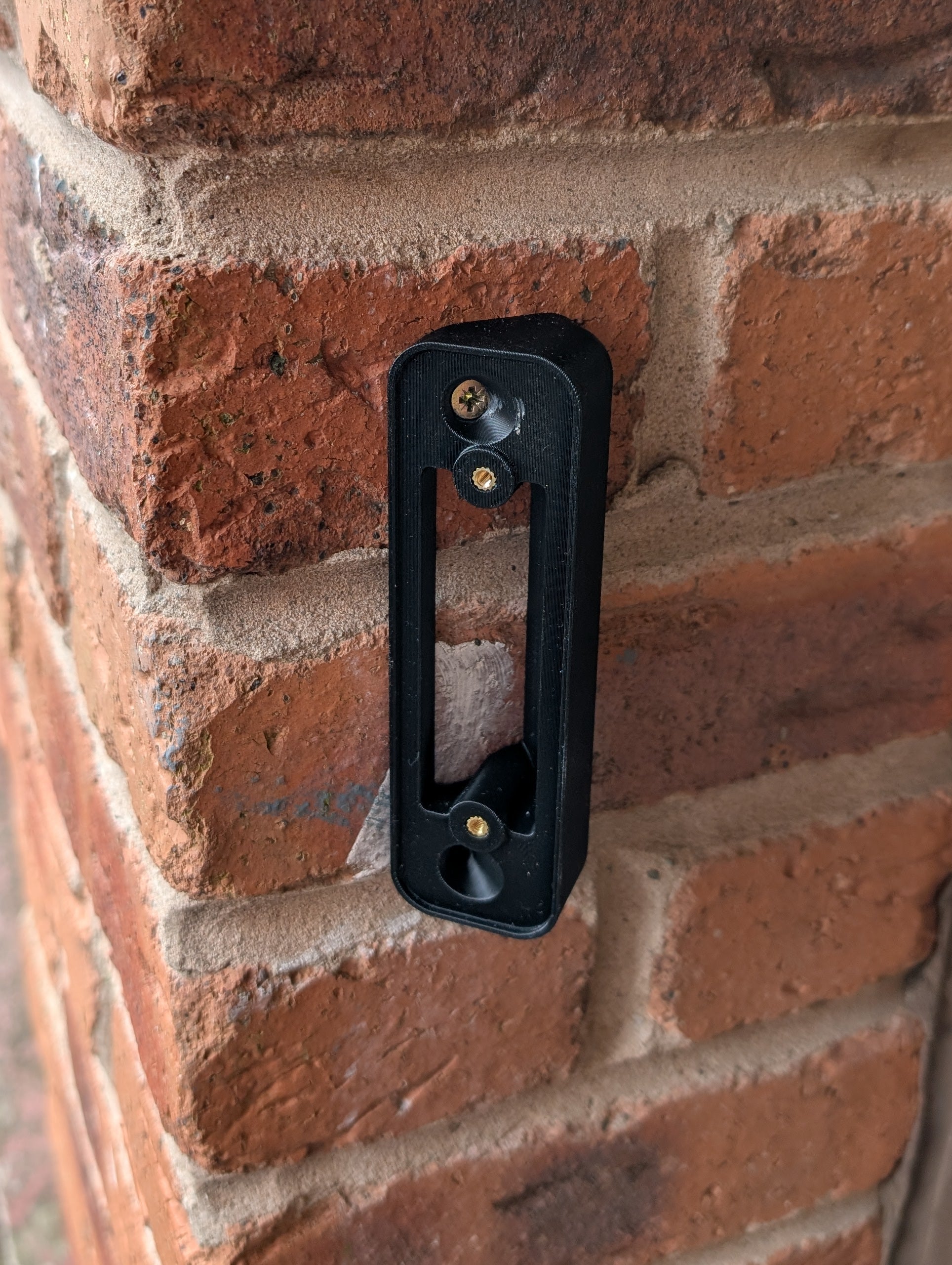 Blink Video Doorbell (Version 1) Reversible Angle Mount, in black. Mounted on wall.