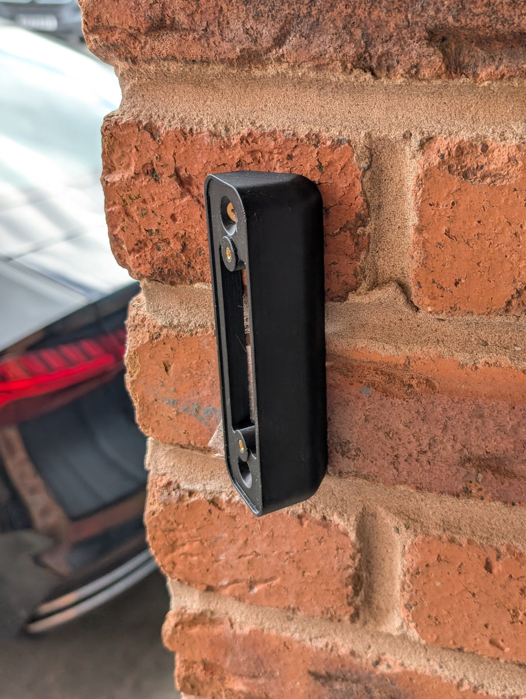 Blink Video Doorbell (Version 1) Reversible Angle Mount, in black. Mounted on wall.