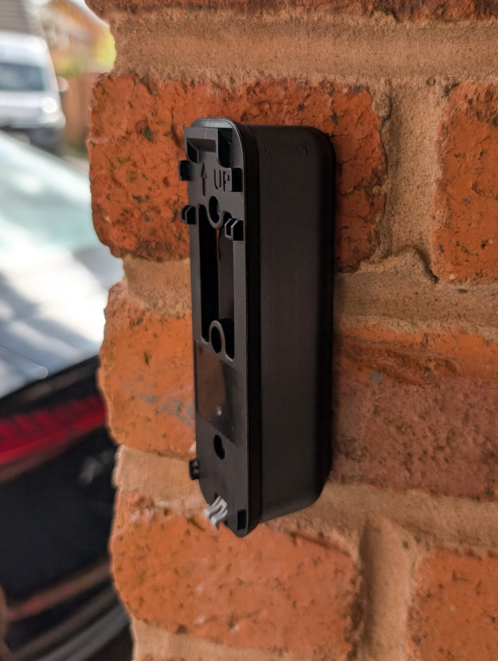 Blink Video Doorbell (Version 1) Reversible Angle Mount, in black. Mounted on wall.