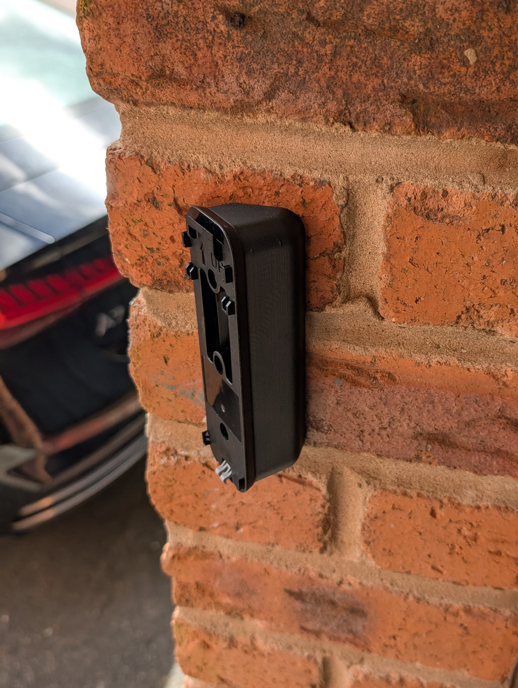Blink Video Doorbell (Version 1) Reversible Angle Mount, in black. Mounted on wall.
