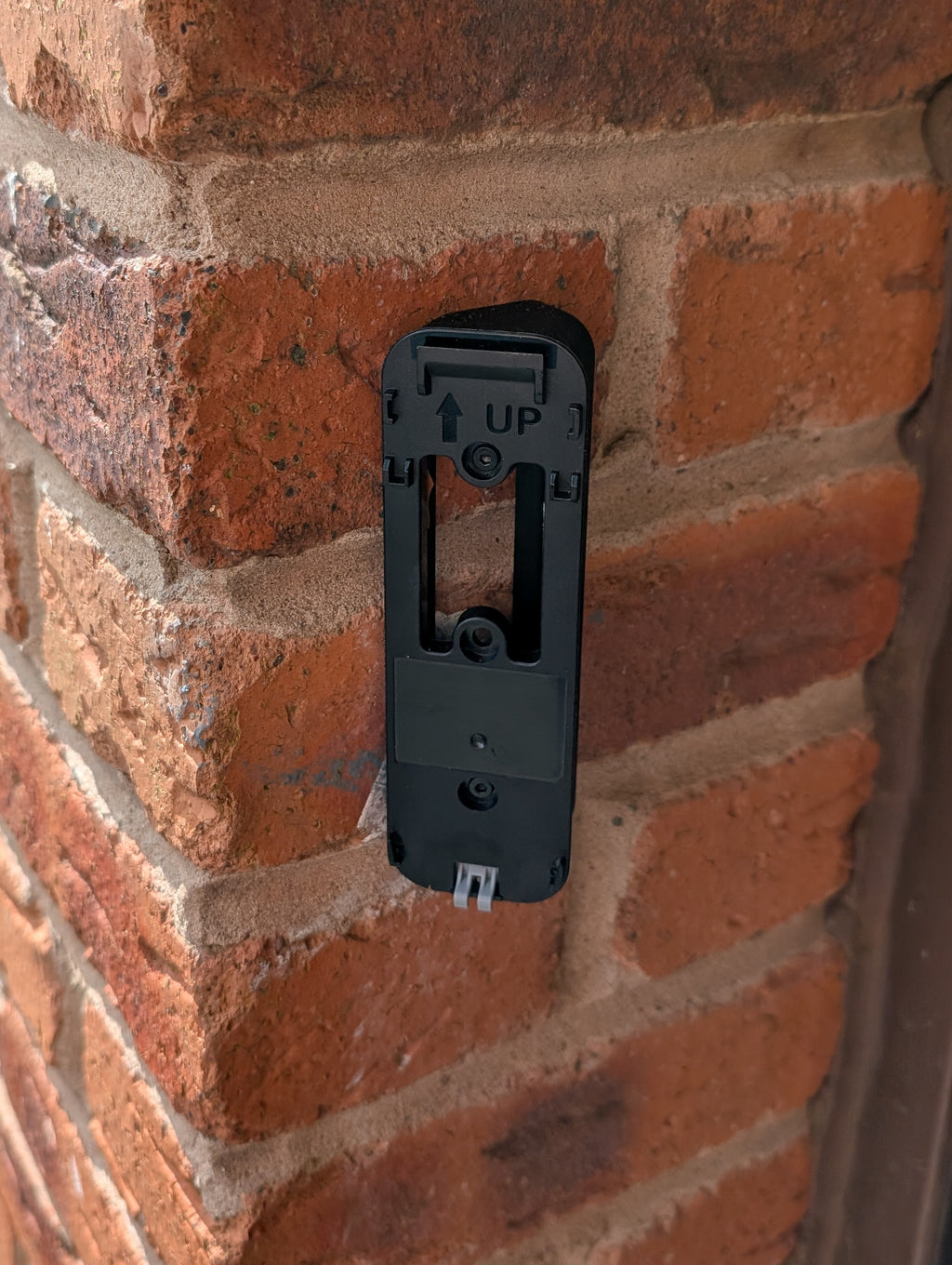 Blink Video Doorbell (Version 1) Reversible Angle Mount, in black. Mounted on wall.
