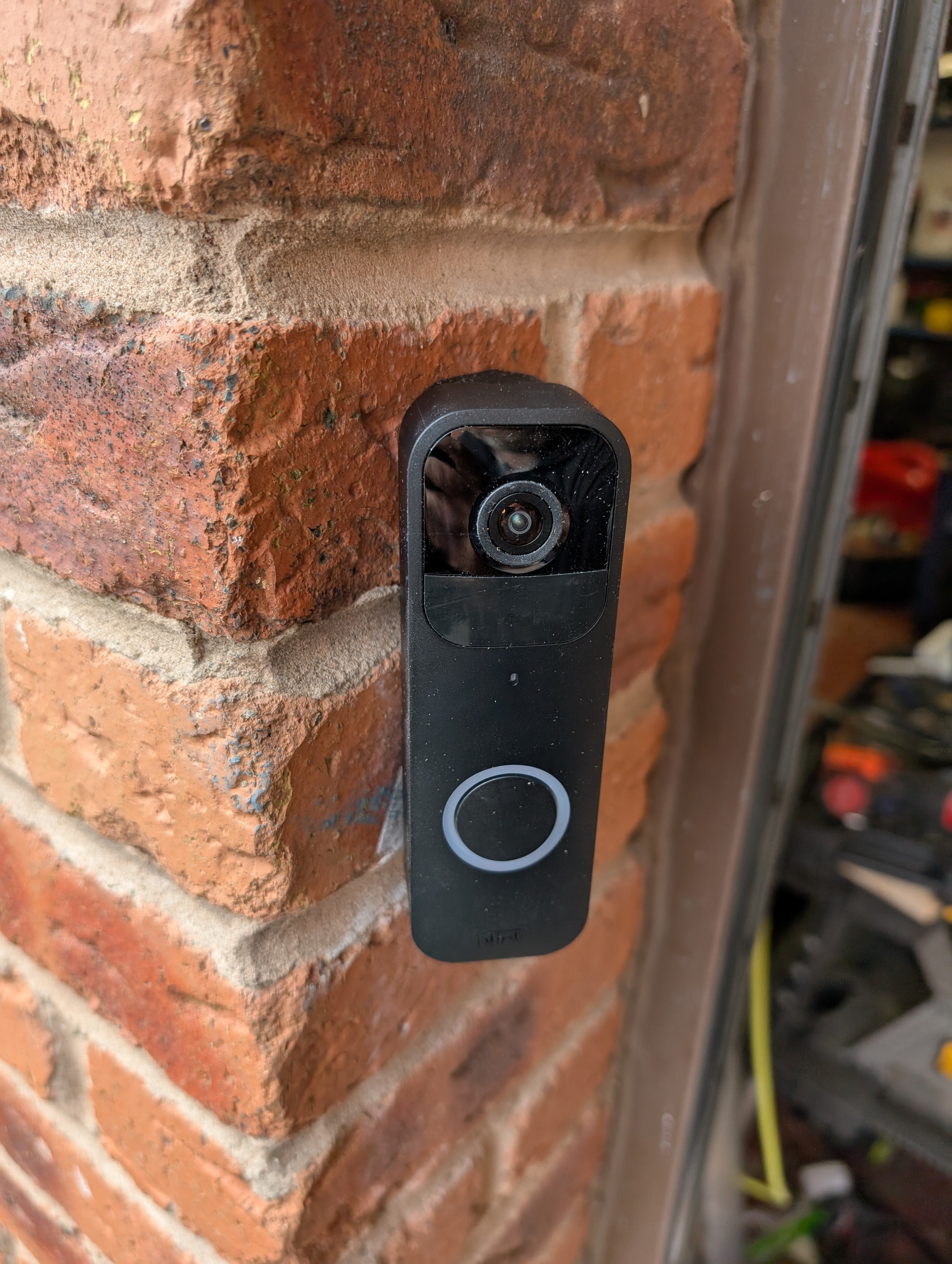 Blink Video Doorbell (Version 1) Reversible Angle Mount, in black. Mounted on wall.
