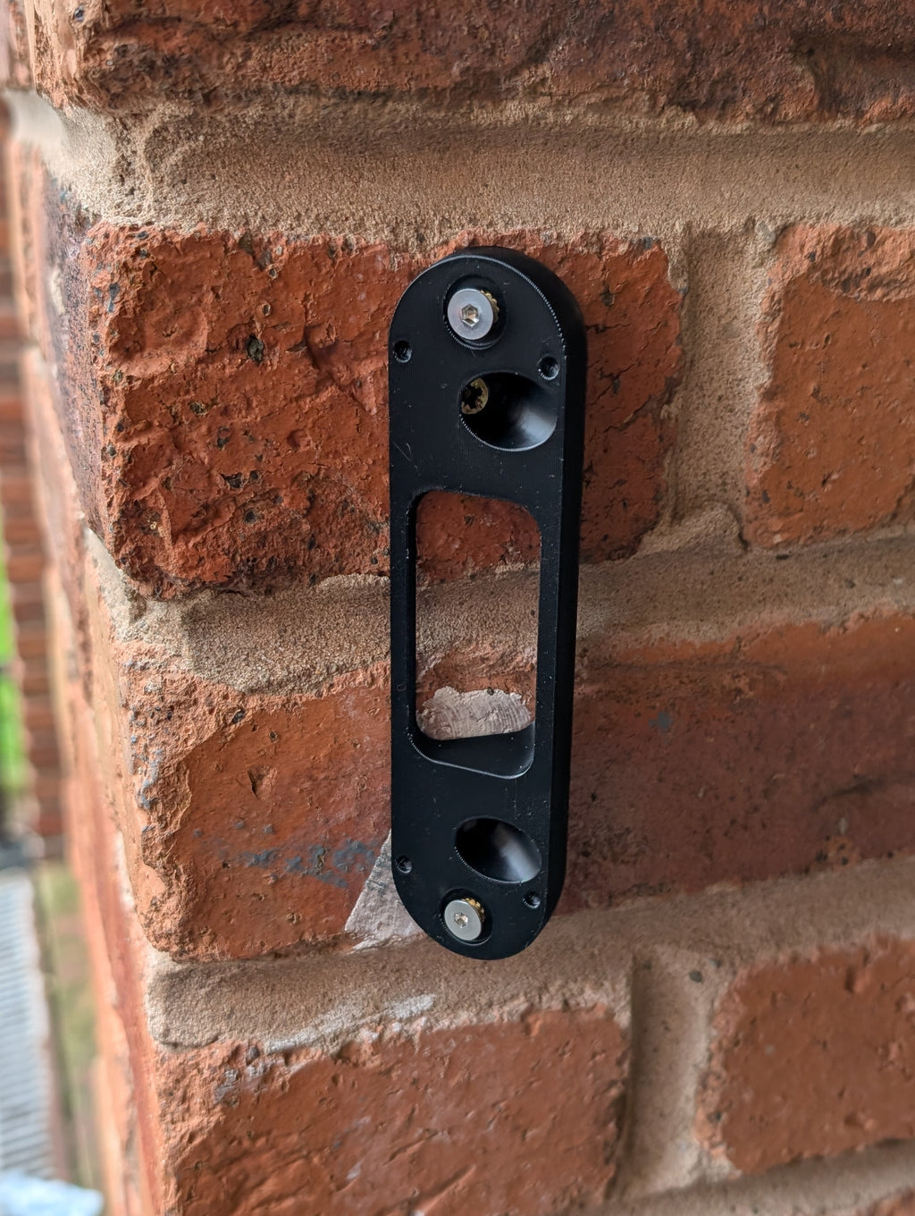 Arlo Essential Video Doorbell Gen 1 Reversible Angle Mount, in black. Mounted on wall.
