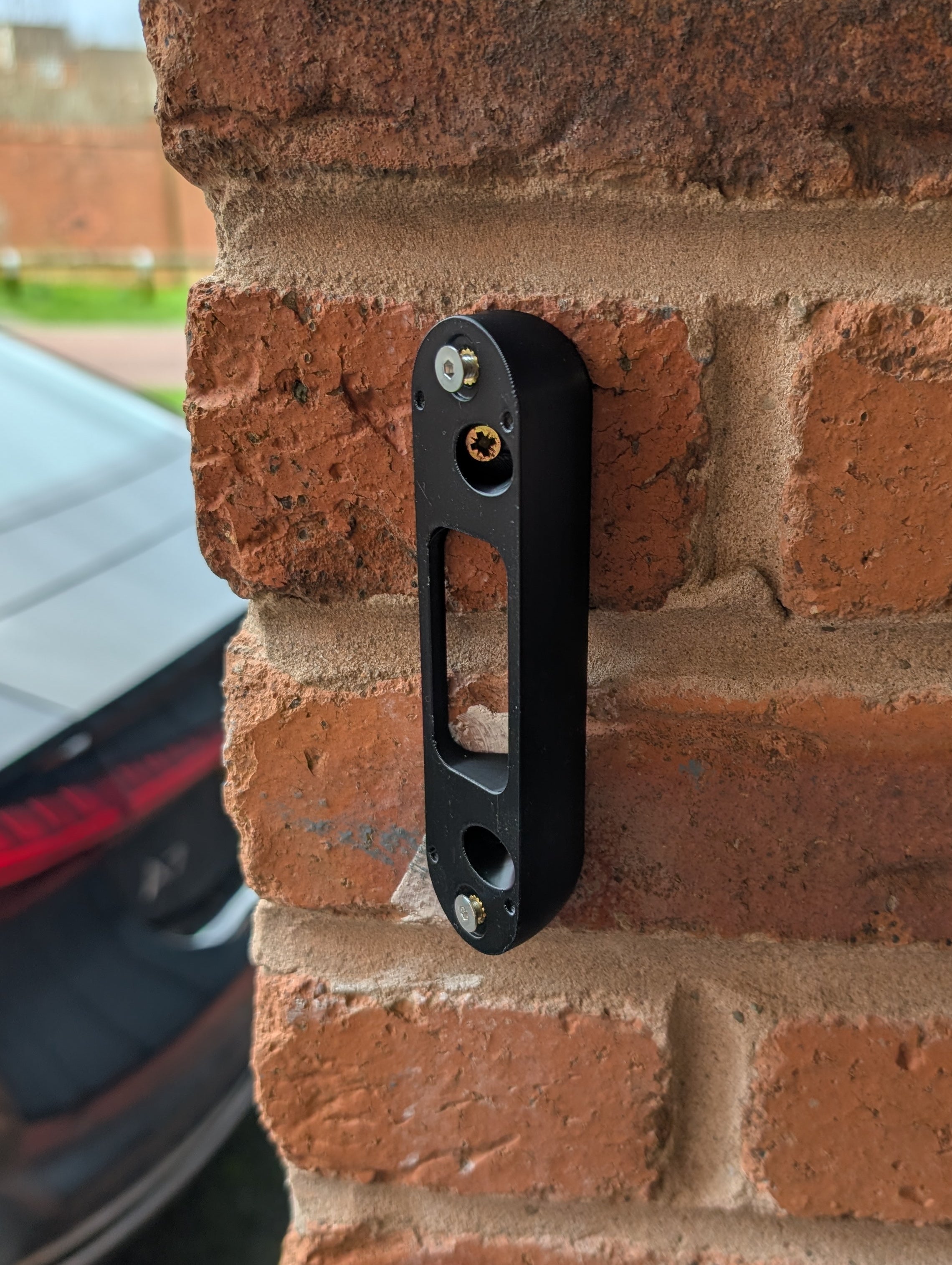 Arlo Essential Video Doorbell Gen 1 Reversible Angle Mount, in black. Mounted on wall.