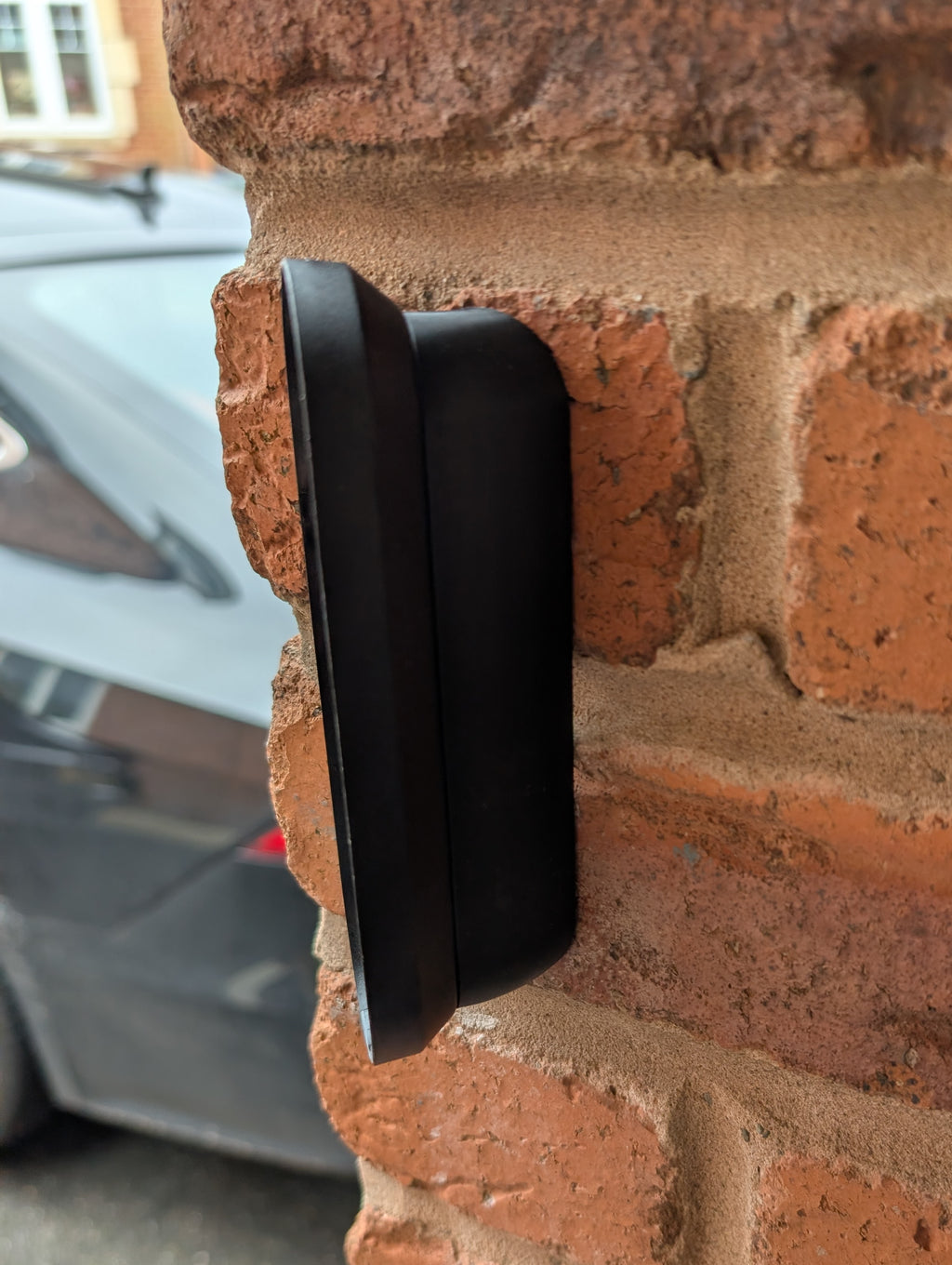 Arlo Essential Video Doorbell Gen 1 Reversible Angle Mount, in black. Mounted on wall.