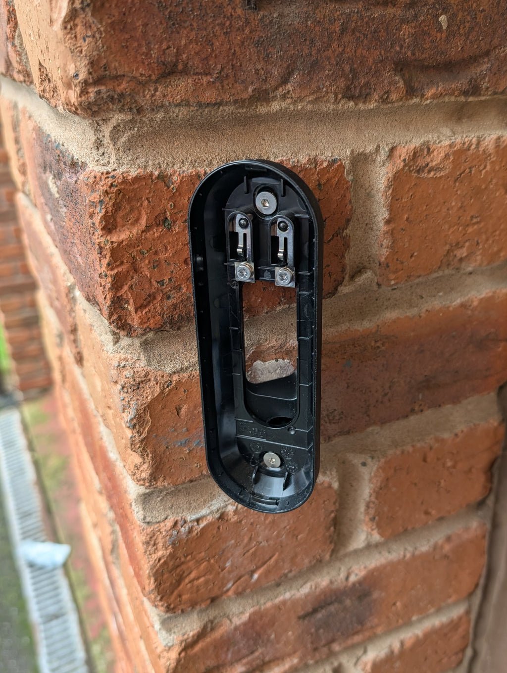 Arlo Essential Video Doorbell Gen 1 Reversible Angle Mount, in black. Mounted on wall.