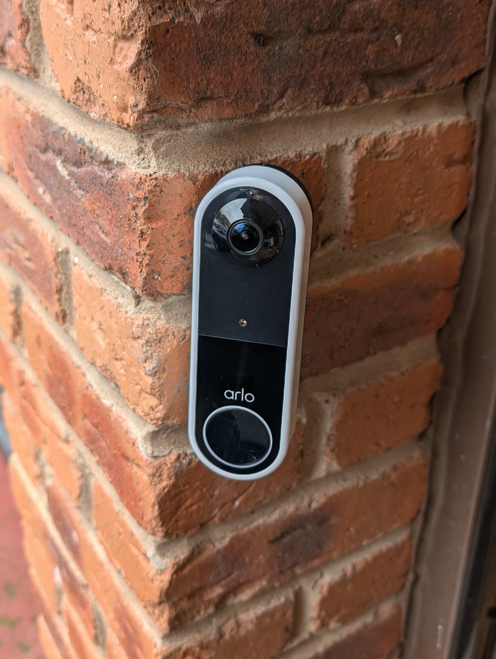 Arlo Essential Video Doorbell Gen 1 Reversible Angle Mount, in black. Mounted on wall.