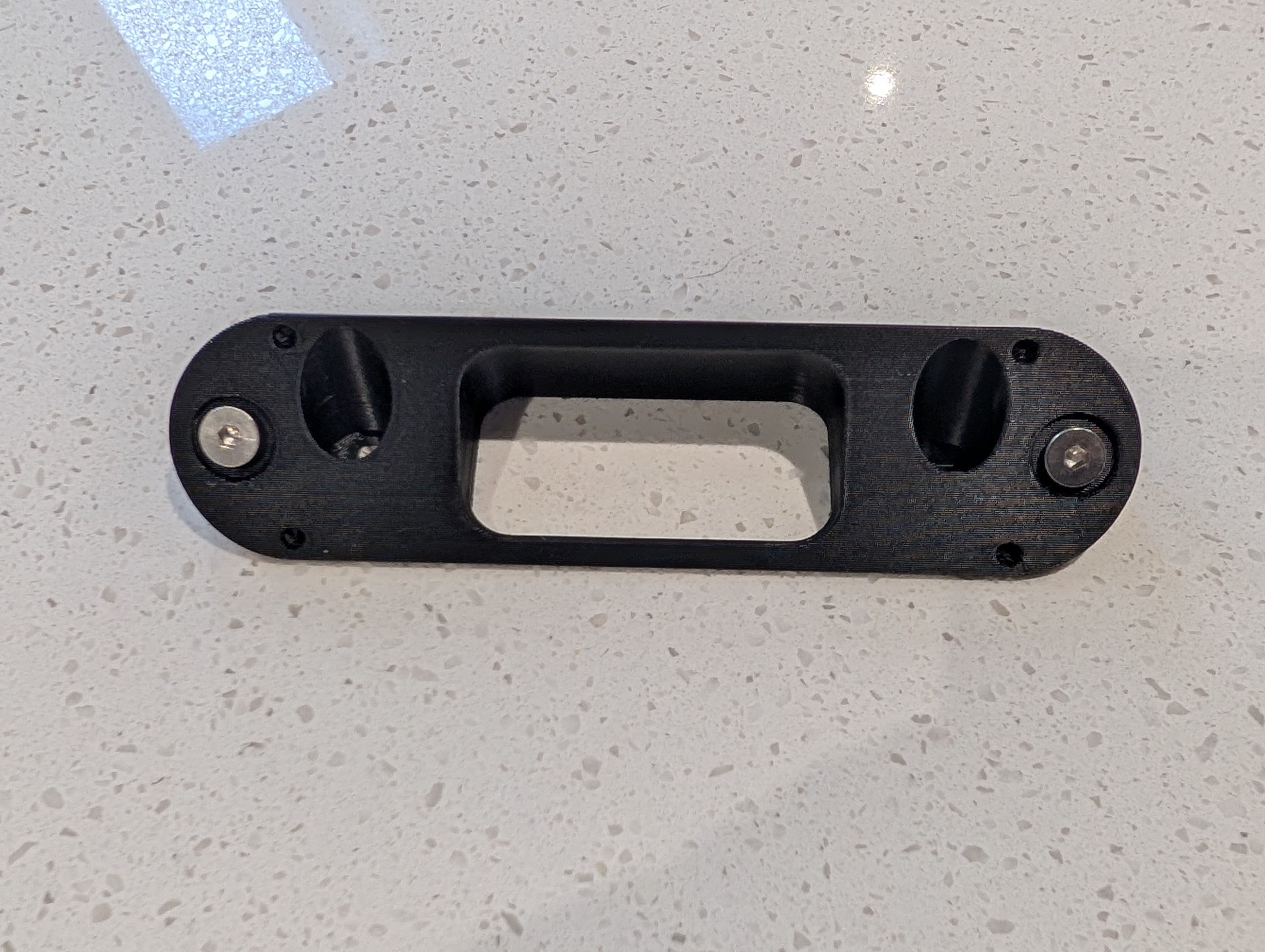 Arlo Essential Video Doorbell Gen 1 Reversible Angle Mount, in black. Unmounted on work surface.