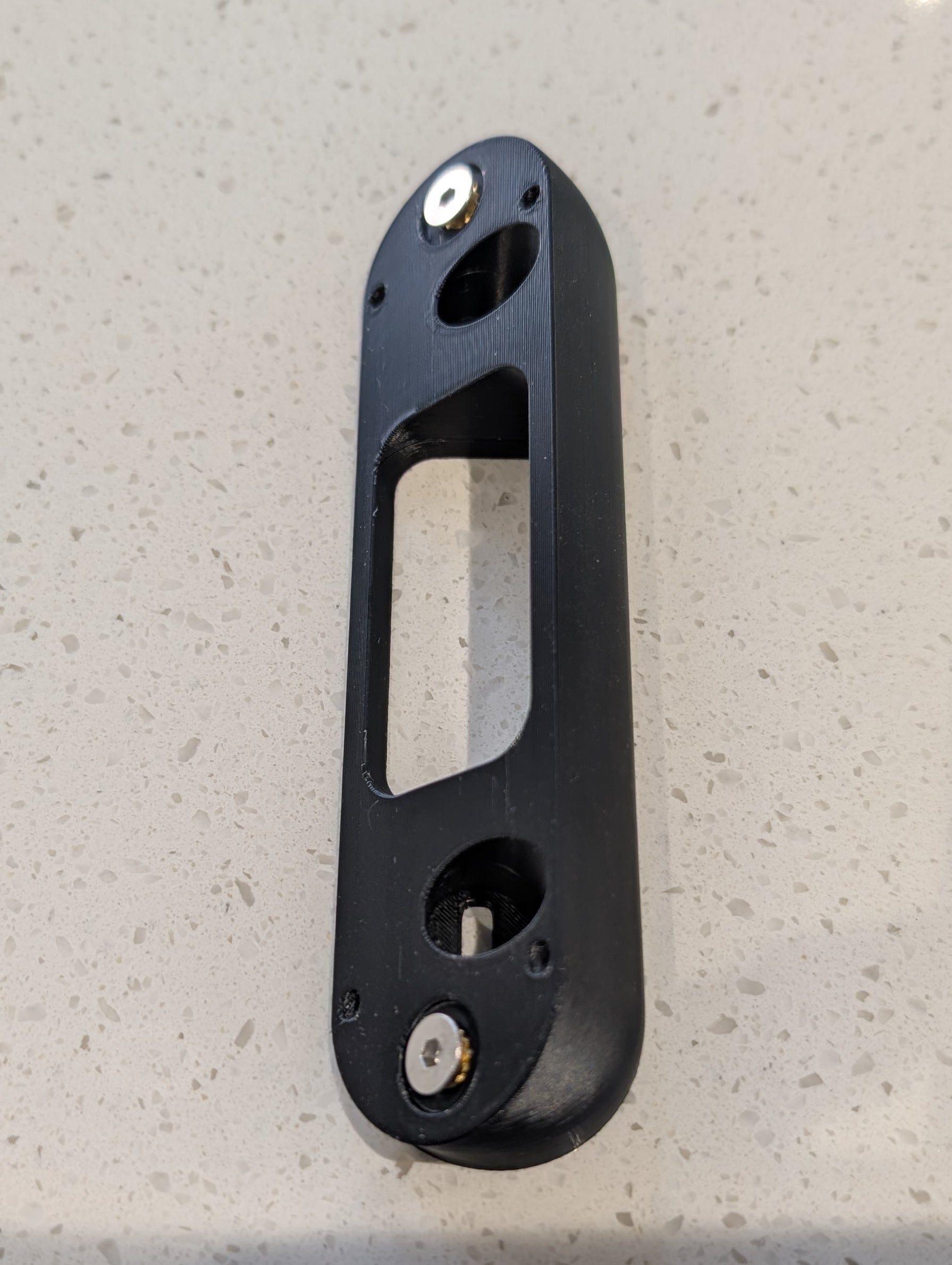 Arlo Essential Video Doorbell Gen 1 Reversible Angle Mount, in black. Unmounted on work surface.